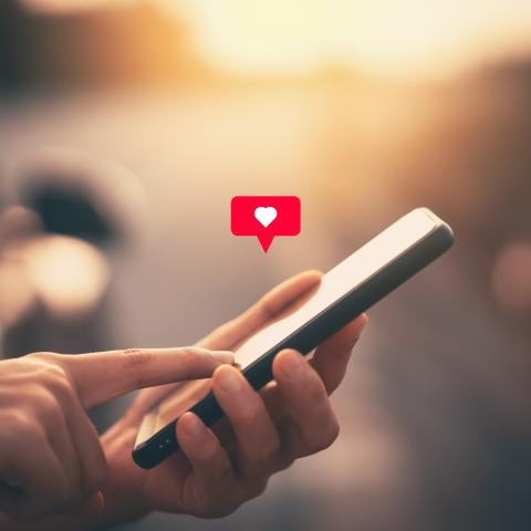 Hands holding phone with heart notification